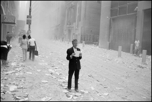 USA. NYC. 9/11/2001. A dazed man picks up a paper that was blown out of the towers after the attack of the World Trade Center, and begins to read it. MAGNUM/Larry Towell